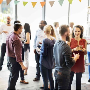 Eine Gruppe von Menschen steht in einem Raum auf einer Party. Ein Mann steht etwas abseits. Er hat noch nicht den Mut Kontakt zu den anderen aufzunehmen.