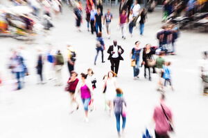 Ein Mann steht inmitten eines vollen Platzes. Wie gelähmt steht er in der Mitte still, während sich um ihn herum alles schnell bewegt. Panikattacken können mit Hypnose aufgelöst werden.