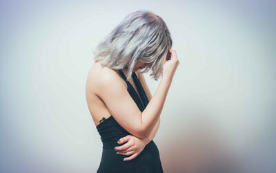 Negative Gefühle und Erfahrungen auflösen. Eine Frau schaut nach unten und hält sich die Hand vor das Gesicht.