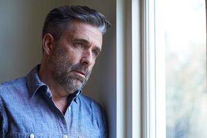 Ein Mann schaut aus dem Fenster. Er ist ohnmächtig, da seine Angst zu groß ist, um nach draußen zu gehen. Mit Hypnose kann er seine generalisierte Angststörung loswerden.