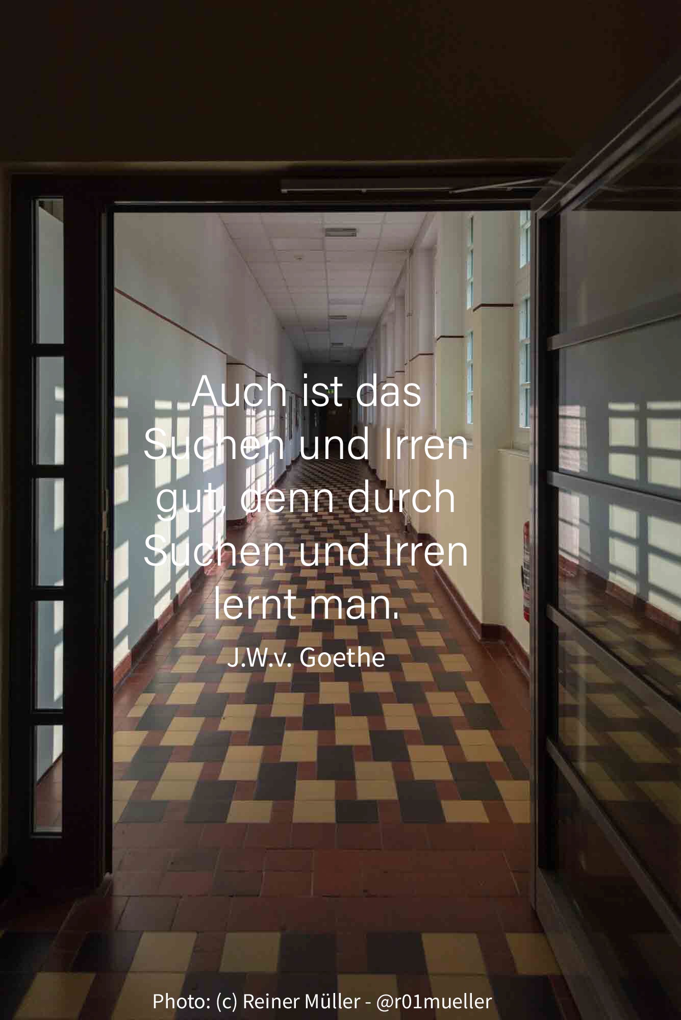 Eine geöffnete Flügeltür, die den Blick auf einen langen, von Fenstern beleuchteten Gang freigibt.